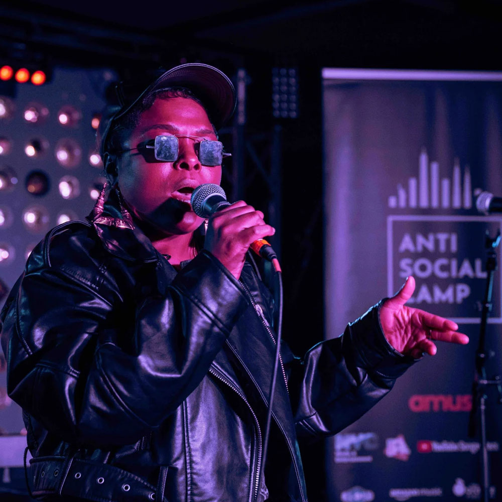 A woman singing into a mic during a live performance.