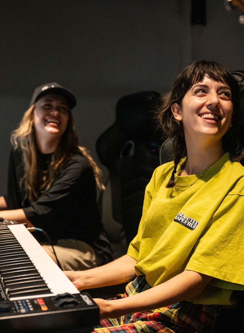 two artists smiling with a piano in front of them