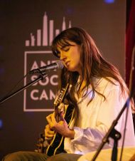 artist singing while playing guitar