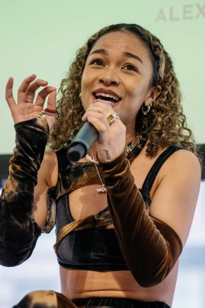an artist smiling and singing into a microphone
